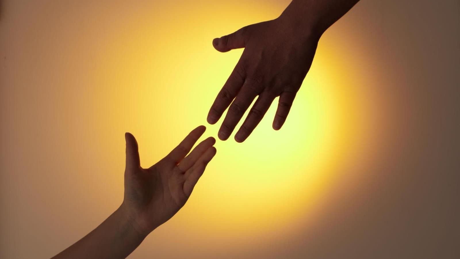 Deux mains se tendant l’une vers l’autre dans une lumière chaleureuse