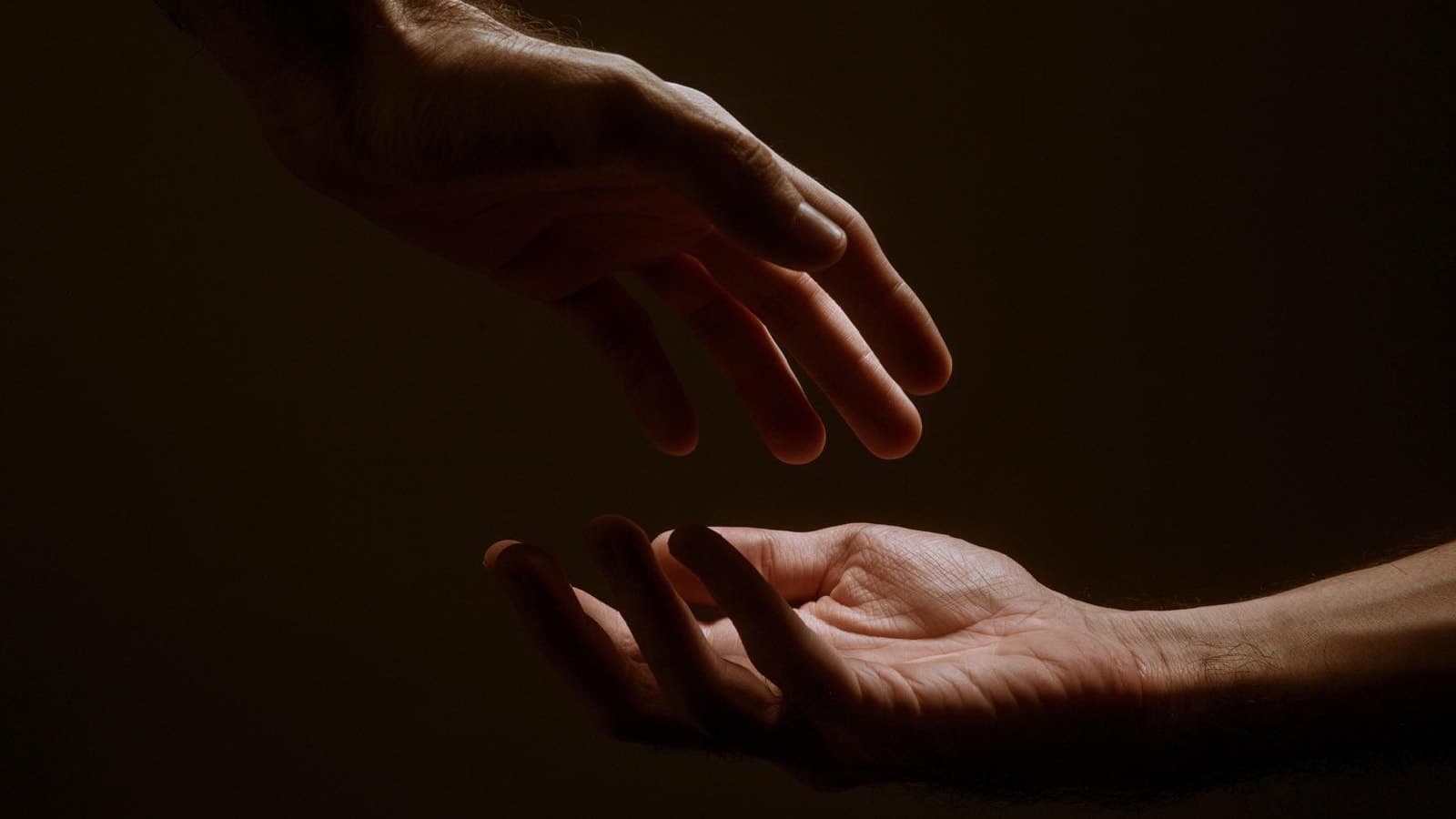 Deux mains ouvertes se tendant l’une vers l’autre dans une lumière douce et chaleureuse